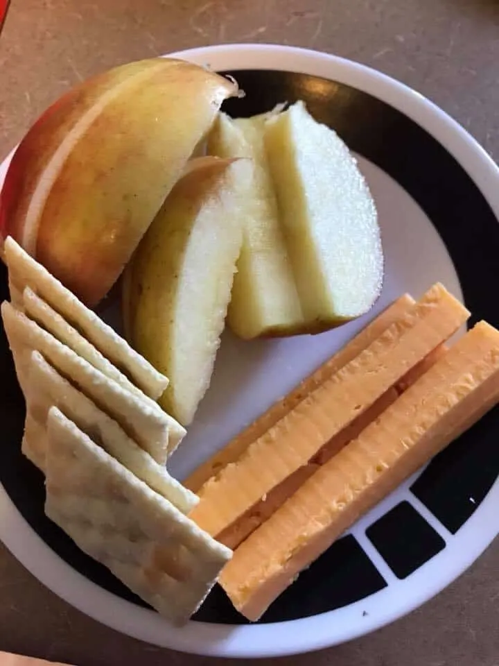 A plate of apples cheese sticks and saltine crackers