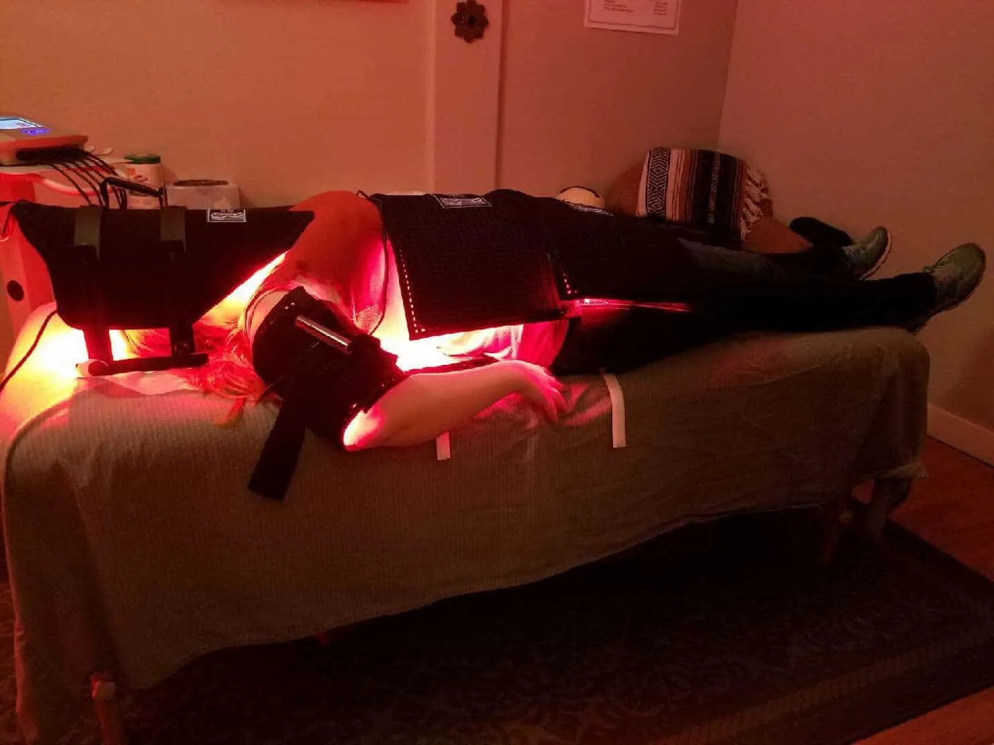 A person laying on a massage table with light contour instruments on the neck, arms, stomach and legs