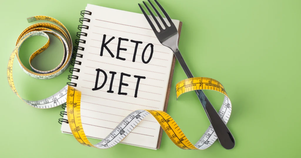 notebook for the keto diet with fork and measuring tape next to it